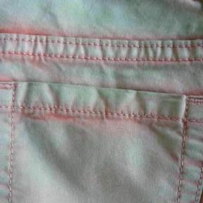 Bicoloured cotton trousers: treated with PERIPRET COV 2 conc. and a green PERICOLOR P pigment by a dip/extract process, afterwards overdyed with a red direct dyeing